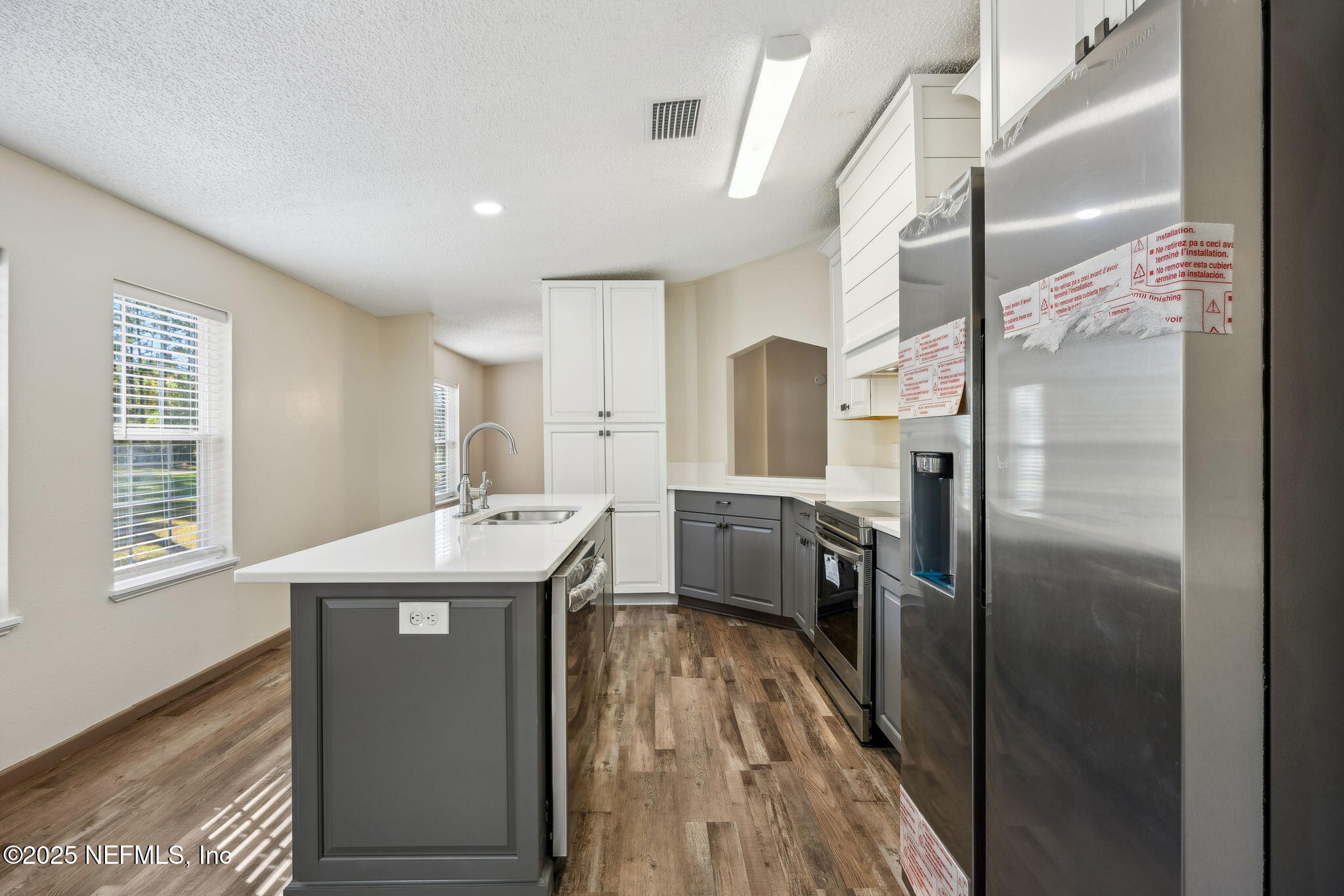 6034 Leona Padgett Road Jacksonville, FL 32234 - Photo 17 of 37 a kitchen with kitchen island a counter top space a sink and a refrigerator