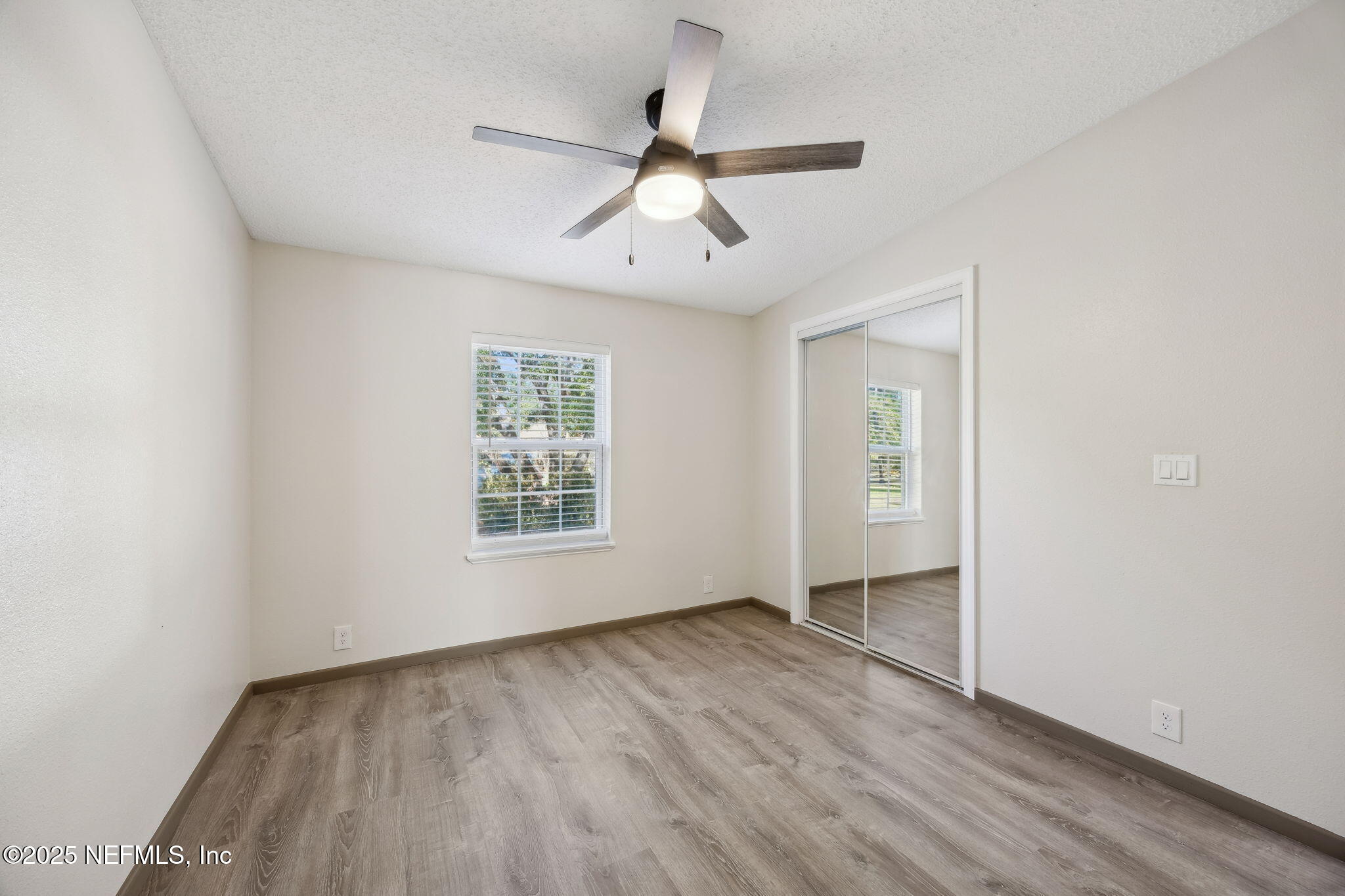 6034 Leona Padgett Road Jacksonville, FL 32234 - Photo 25 of 37 an empty room with wooden floor ceiling fan and windows