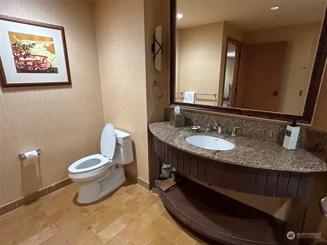 a bathroom with a granite countertop toilet a sink and a mirror