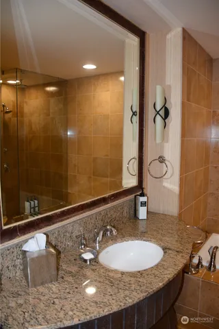 a bathroom with a granite countertop sink a mirror and shower