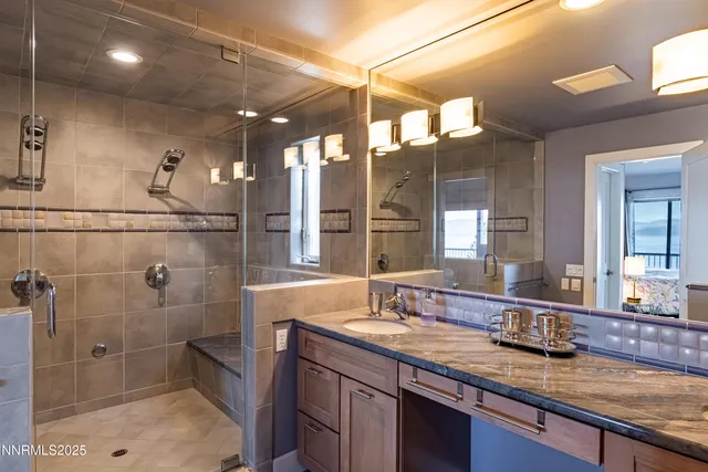 a bathroom with a granite countertop sink a mirror and shower