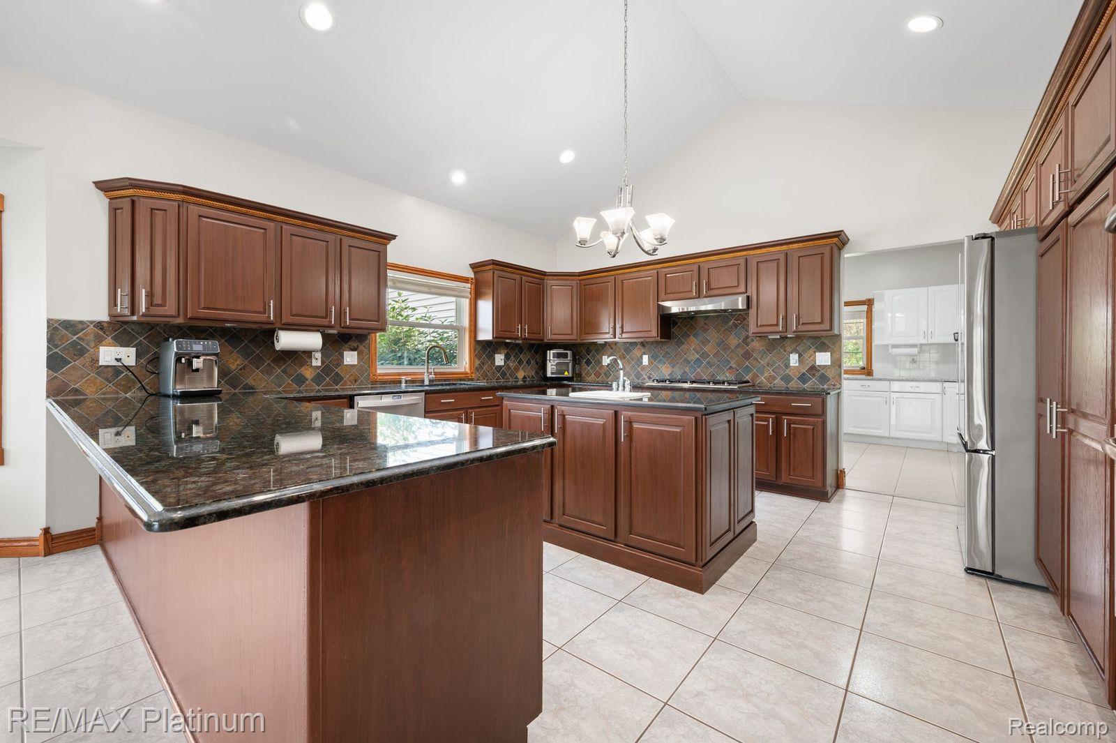 8922 McClements Road Brighton, MI 48114 - Photo 3 of 65 Kitchen featuring dark wood-finish cabinetry, dark stone countertops, and a full-height tile backsplash