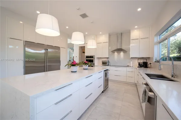 a kitchen with stainless steel appliances kitchen island granite countertop a sink and a refrigerator