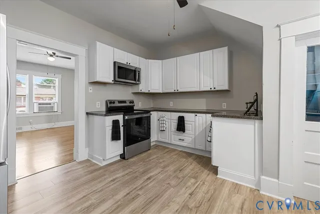 a kitchen with stainless steel appliances granite countertop a refrigerator a stove top oven a sink and dishwasher with wooden floor