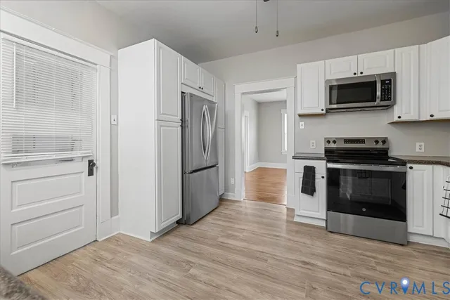 a kitchen with stainless steel appliances white cabinets and a stove top oven