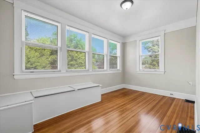 a view of an empty room with wooden floor and a window