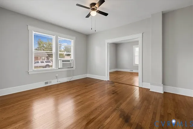 a view of an empty room with wooden floor and a window