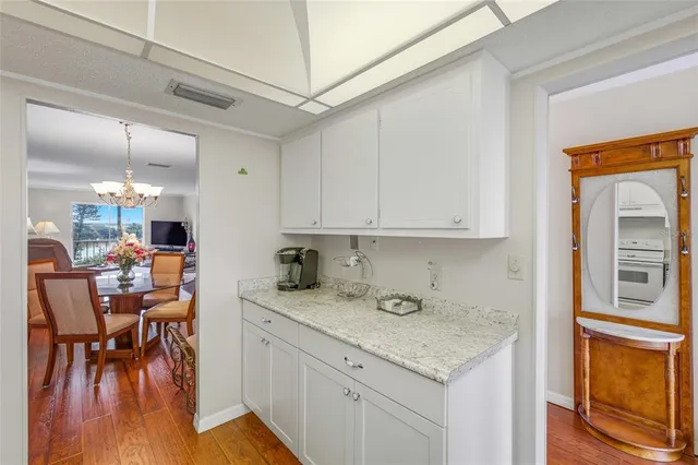 a kitchen with stainless steel appliances granite countertop a stove top oven a sink a dining table and chairs with wooden floor