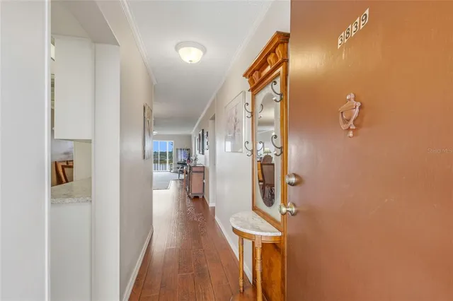 a view of a hallway with wooden floor and a bathroom