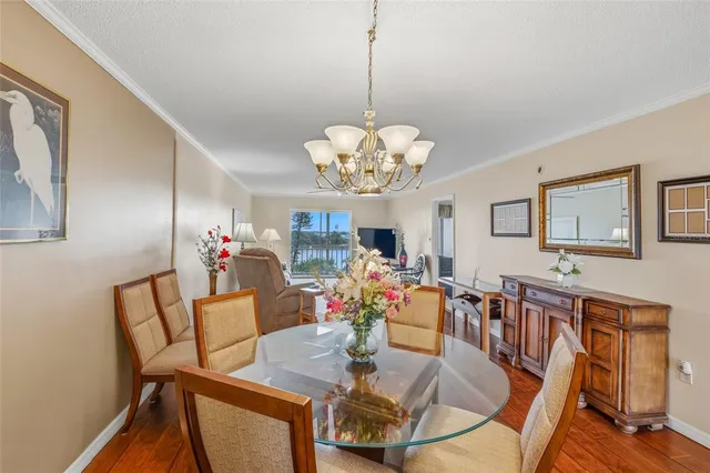 a dining room with wooden floor a chandelier a glass table and chairs