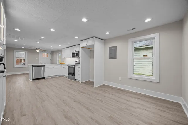 a view of an empty room with a window and wooden floor
