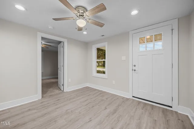 an empty room with wooden floor and ceiling fan