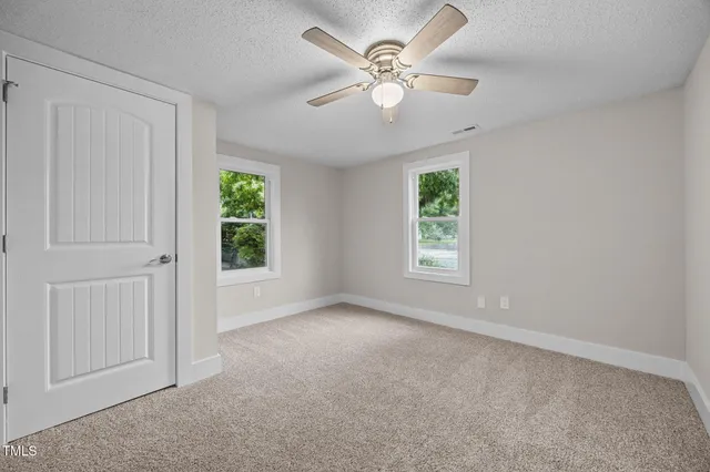 an empty room with windows and fan