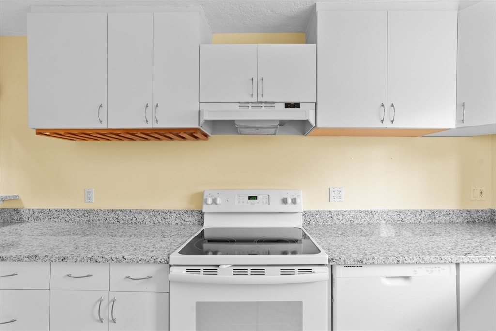 26 Westgate Road, Unit 264 Chestnut Hill, MA 02467 - Photo 7 of 30 a white kitchen with granite countertop stainless steel appliances