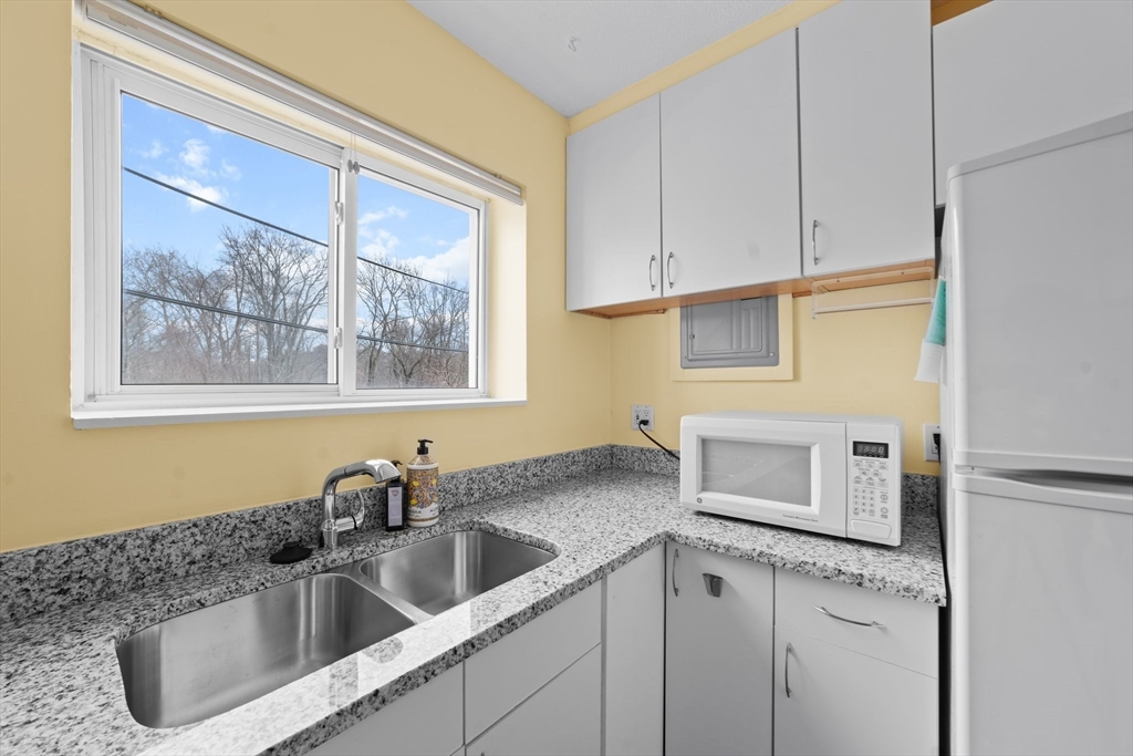 26 Westgate Road, Unit 264 Chestnut Hill, MA 02467 - Photo 8 of 30 a close view of a sink a microwave and cabinets in a kitchen
