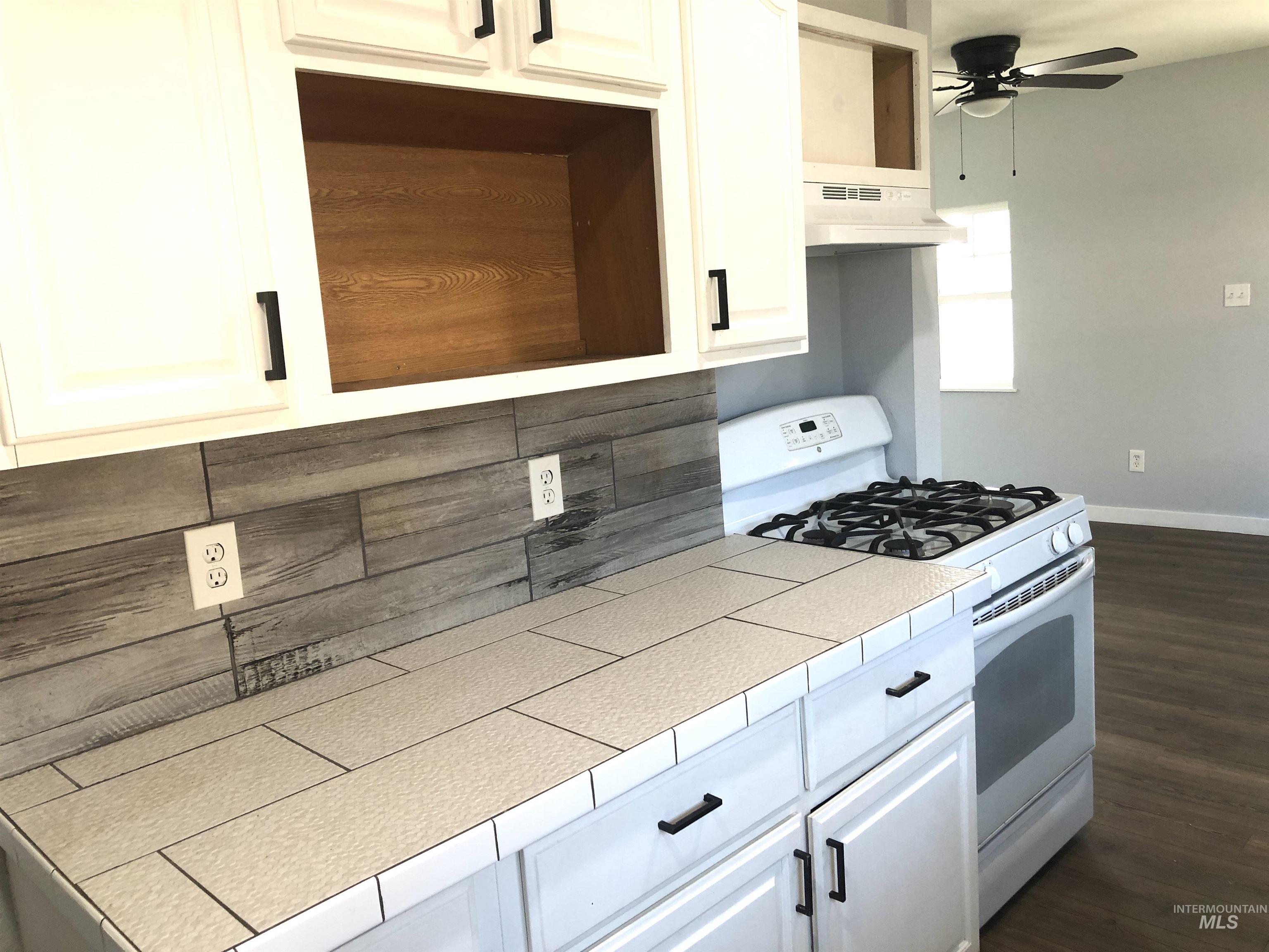 717 10th Street Clarkston, WA 99403 - Photo 7 of 23 Kitchen with white range with gas cooktop, dark wood-type flooring, a ceiling fan, and white cabinets