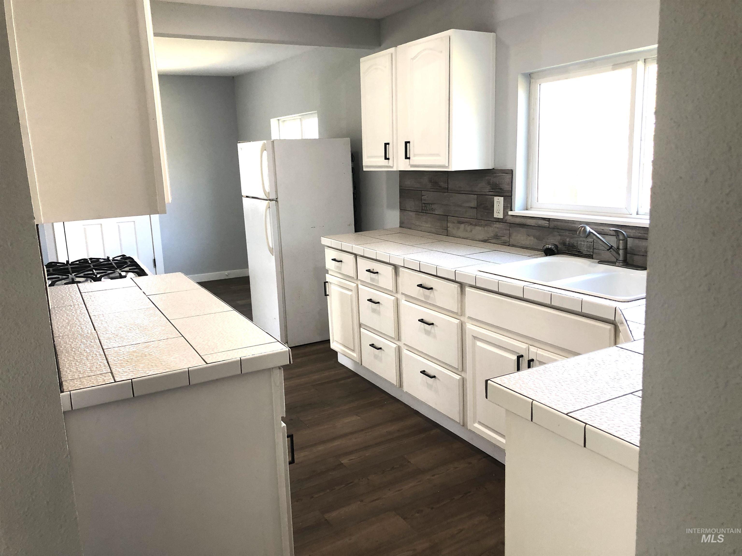 717 10th Street Clarkston, WA 99403 - Photo 9 of 23 Kitchen with tasteful backsplash, dark wood-type flooring, freestanding refrigerator, and tile counters