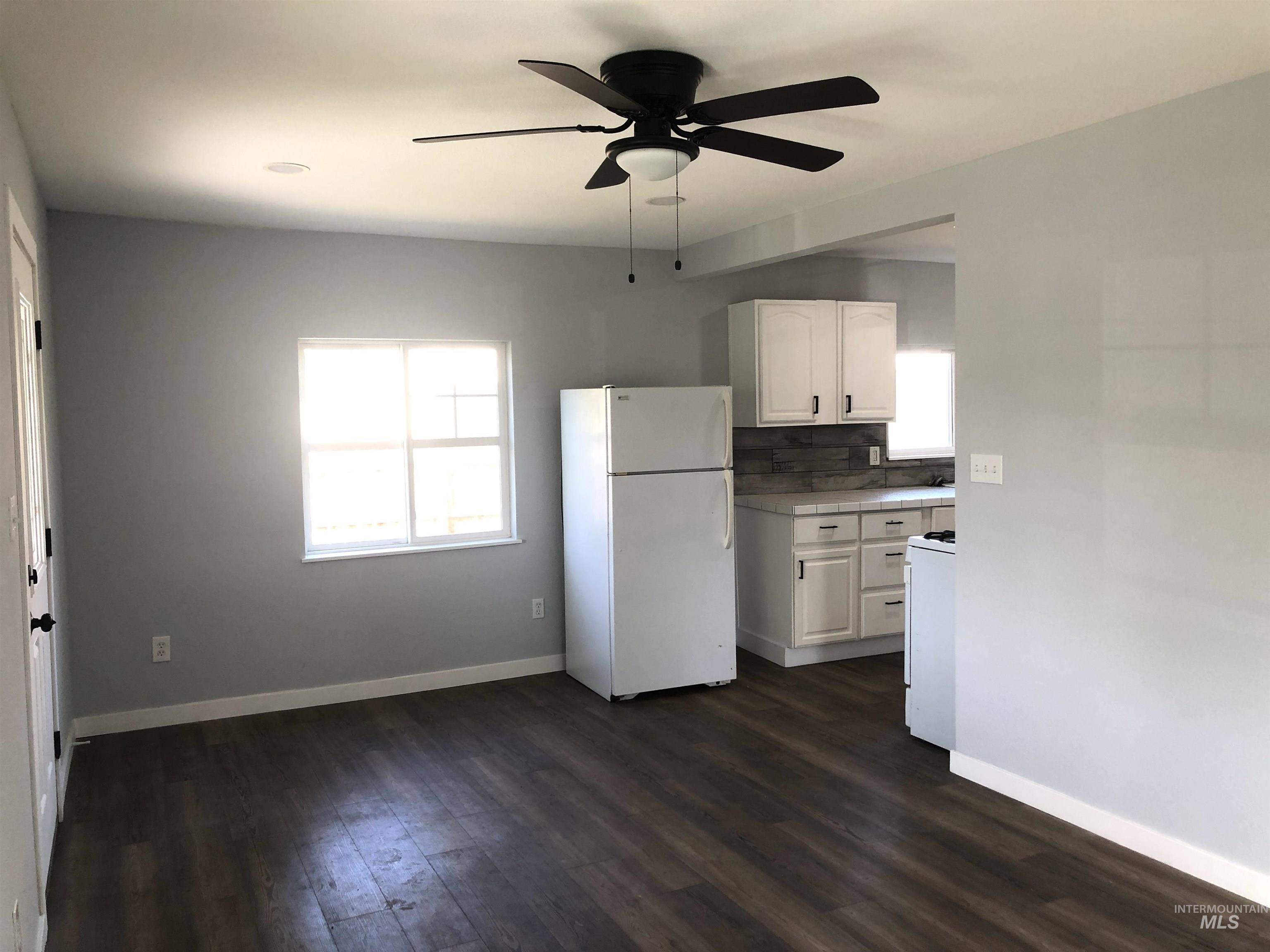 717 10th Street Clarkston, WA 99403 - Photo 10 of 23 Kitchen featuring white appliances, ceiling fan, white cabinets, and dark wood finished floors