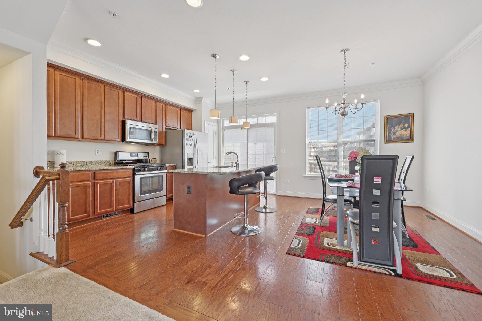 7206 Wood Meadow Way Lanham, MD 20706 - Photo 29 of 61 a kitchen with stainless steel appliances granite countertop a refrigerator a stove top oven a dining table and chairs with wooden floor