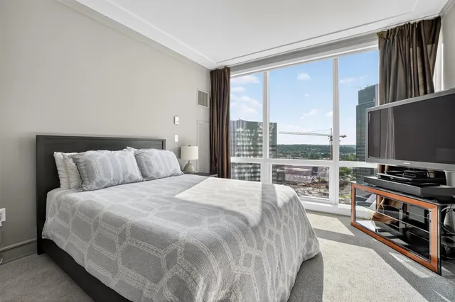 a bedroom with a bed a television and large window