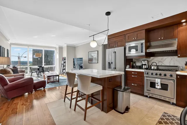 a kitchen with stainless steel appliances granite countertop a stove a sink dishwasher a dining table and chairs with wooden floor