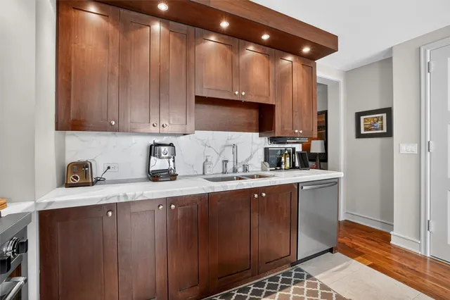 a kitchen with granite countertop a sink cabinets and stainless steel appliances