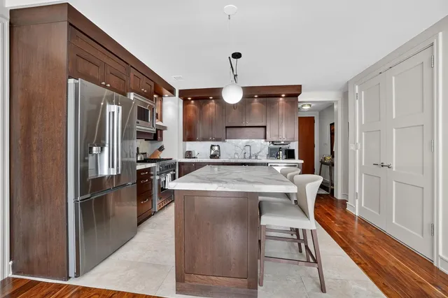 a kitchen with kitchen island a stove a refrigerator and a sink with wooden floor