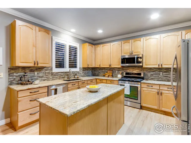 a kitchen with kitchen island granite countertop a sink cabinets and stainless steel appliances