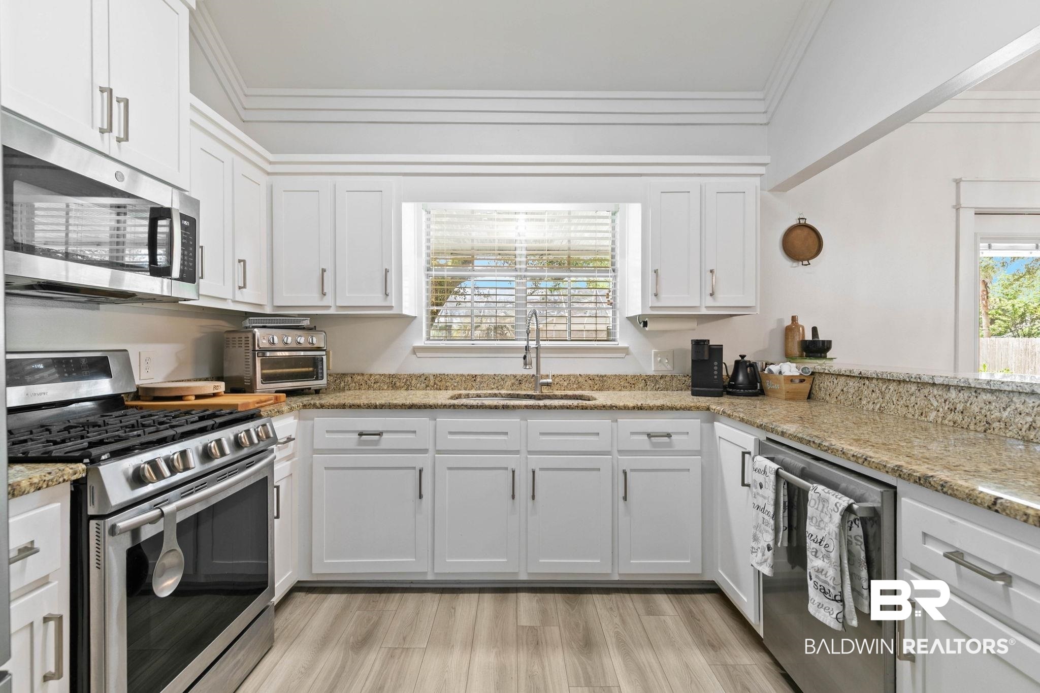520 Juniper Place Drive Foley, AL 36535 - Photo 34 of 35 Kitchen featuring white shaker cabinetry, stainless steel appliances, speckled stone countertops, wood-finish flooring, and crown molding