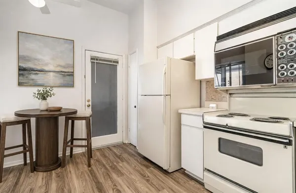 a kitchen with stainless steel appliances a stove a refrigerator and a dining table with wooden floor