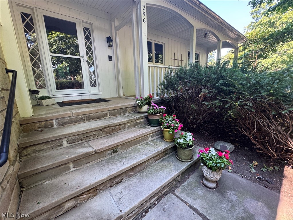 Stone steps leading to an arched covered entry with a white paneled front door featuring decorative glass sidelights