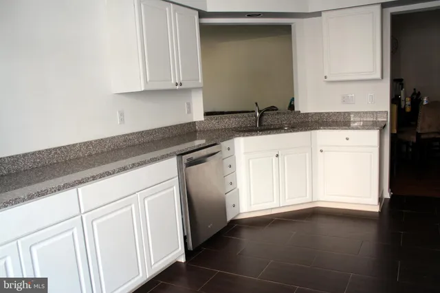 a white kitchen with granite countertop white cabinets and a granite counter tops