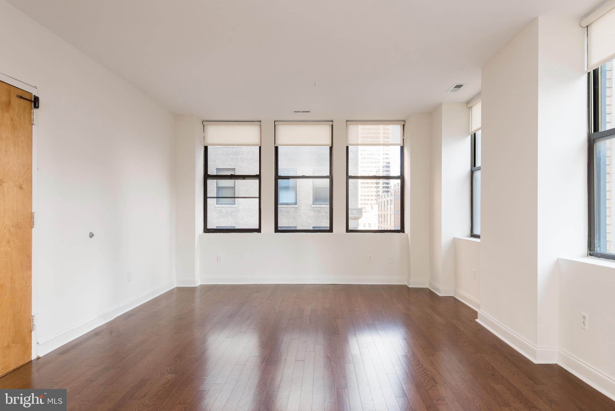 220 South 16th Street, Unit 1102 Philadelphia, PA 19102 - Photo 6 of 26 an empty room with wooden floor and windows