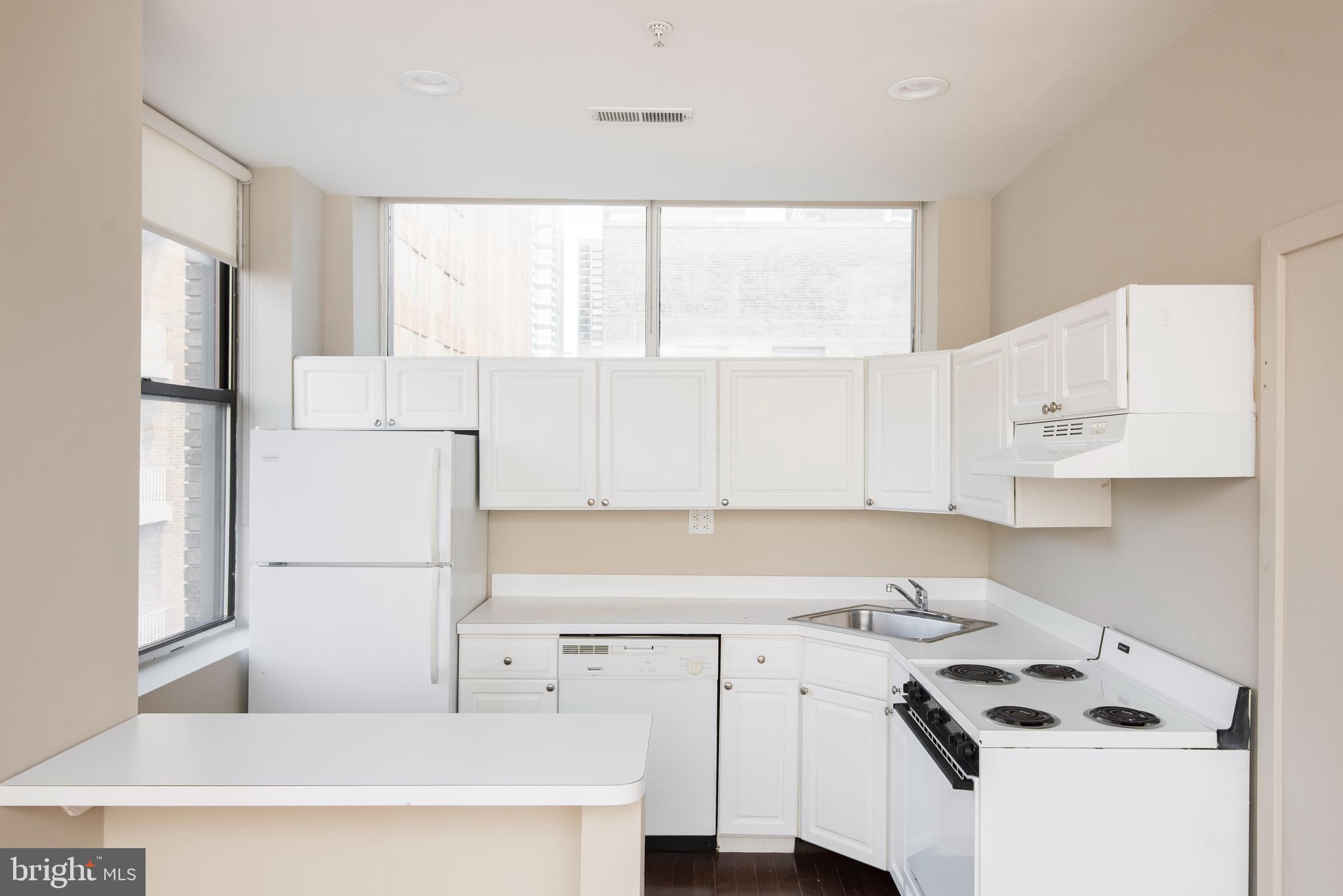220 South 16th Street, Unit 1102 Philadelphia, PA 19102 - Photo 10 of 26 a kitchen with a refrigerator a stove a sink and white cabinets with wooden floor