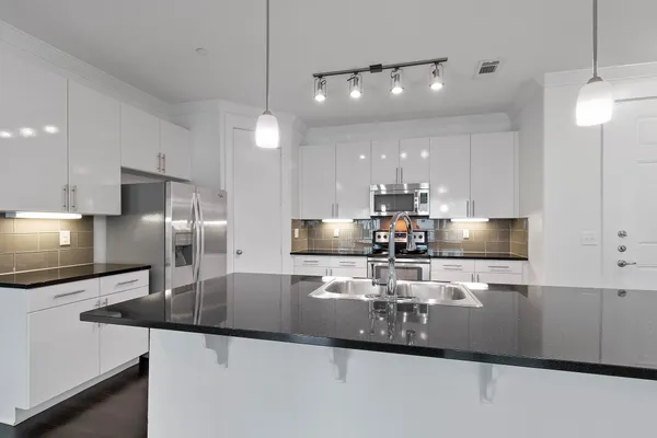 a kitchen with stainless steel appliances granite countertop a sink a stove and a refrigerator