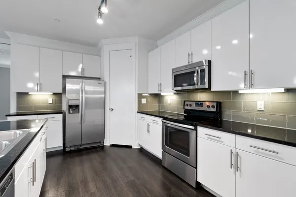 a kitchen with stainless steel appliances granite countertop a stove a refrigerator and a microwave