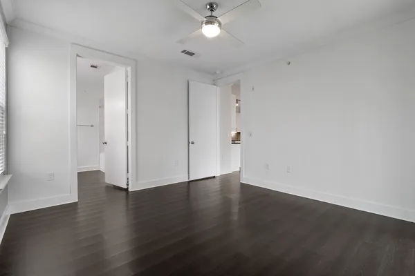 a view of an empty room with wooden floor and a ceiling fan