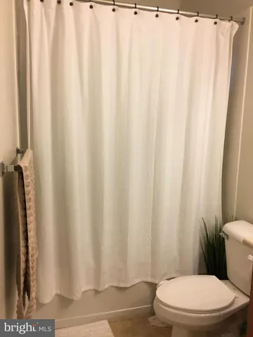 a white toilet sitting next to a white curtain