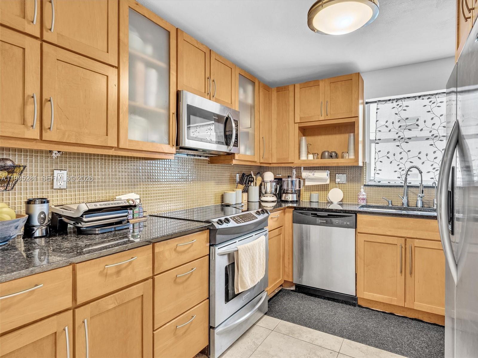 1236 Alton Road, Unit 304 Miami Beach, FL 33139 - Photo 11 of 28 a kitchen with stainless steel appliances granite countertop a sink a stove a microwave and cabinets