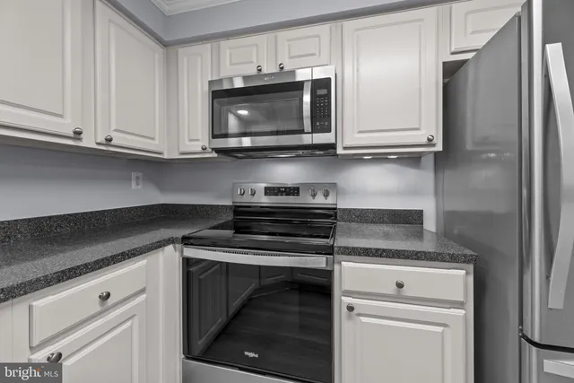 a kitchen with white cabinets and stainless steel appliances