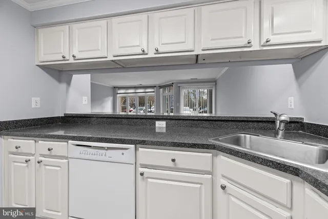 a kitchen with granite countertop white cabinets and a sink