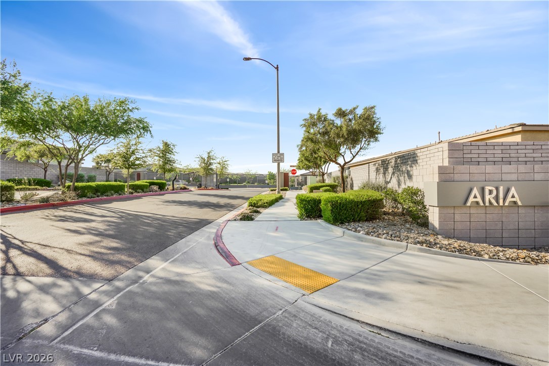 9398 Noble Fir Rdg Court Las Vegas, NV 89143 - Photo 32 of 36 Enter the Aria community, featuring a welcoming stone entrance and well-maintained landscaping.