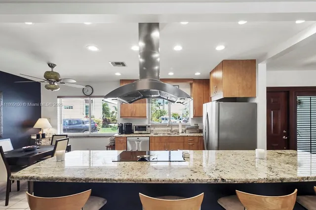 a kitchen with granite countertop kitchen island stainless steel appliances a sink stove and refrigerator