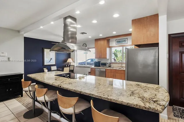 a kitchen with granite countertop kitchen island stainless steel appliances a sink stove and refrigerator