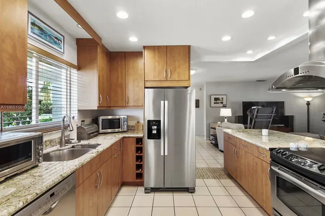 a large kitchen with stainless steel appliances granite countertop a stove top oven a refrigerator a sink and dishwasher