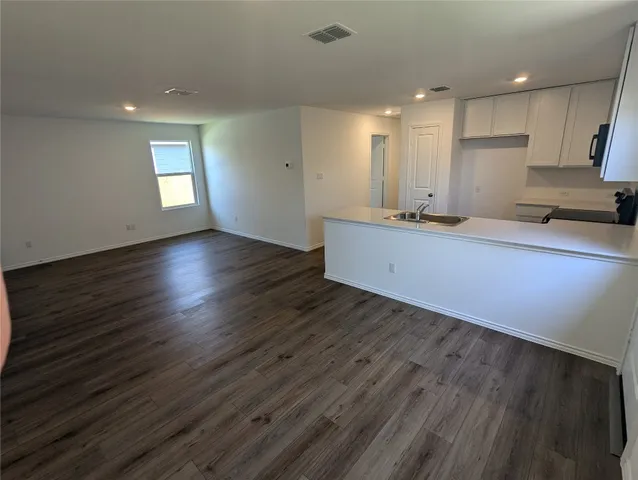 a kitchen with wooden floors a refrigerator a sink a stove a microwave and island