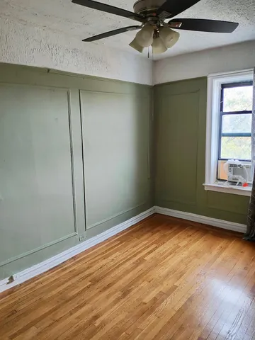 an empty room with wooden floor fan and windows