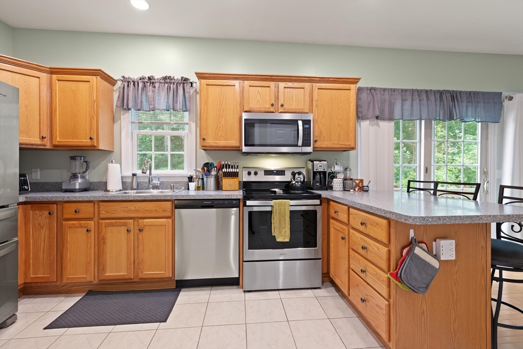 3 Knowlton Circle, Unit 3 Upton, MA 01568 - Photo 18 of 42 a kitchen with stainless steel appliances granite countertop a stove top oven a sink dishwasher a refrigerator and a microwave oven with granite countertops