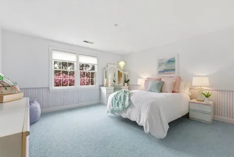 a spacious bedroom with a bed table and a window