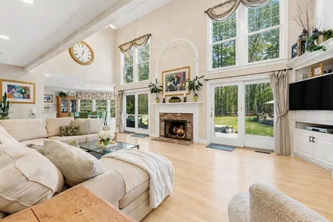 a living room with furniture a fireplace and a flat tv screen next to a window